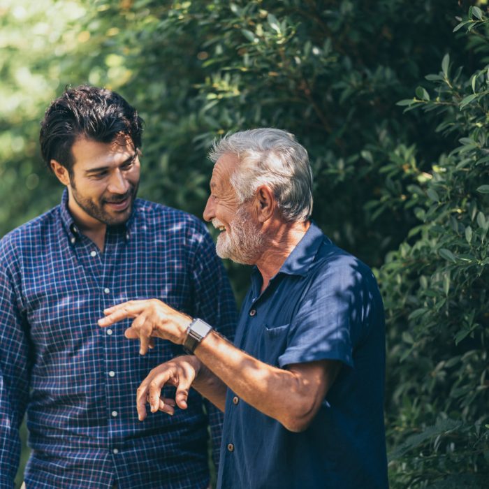 old father and adult son are relaxing in the backyard